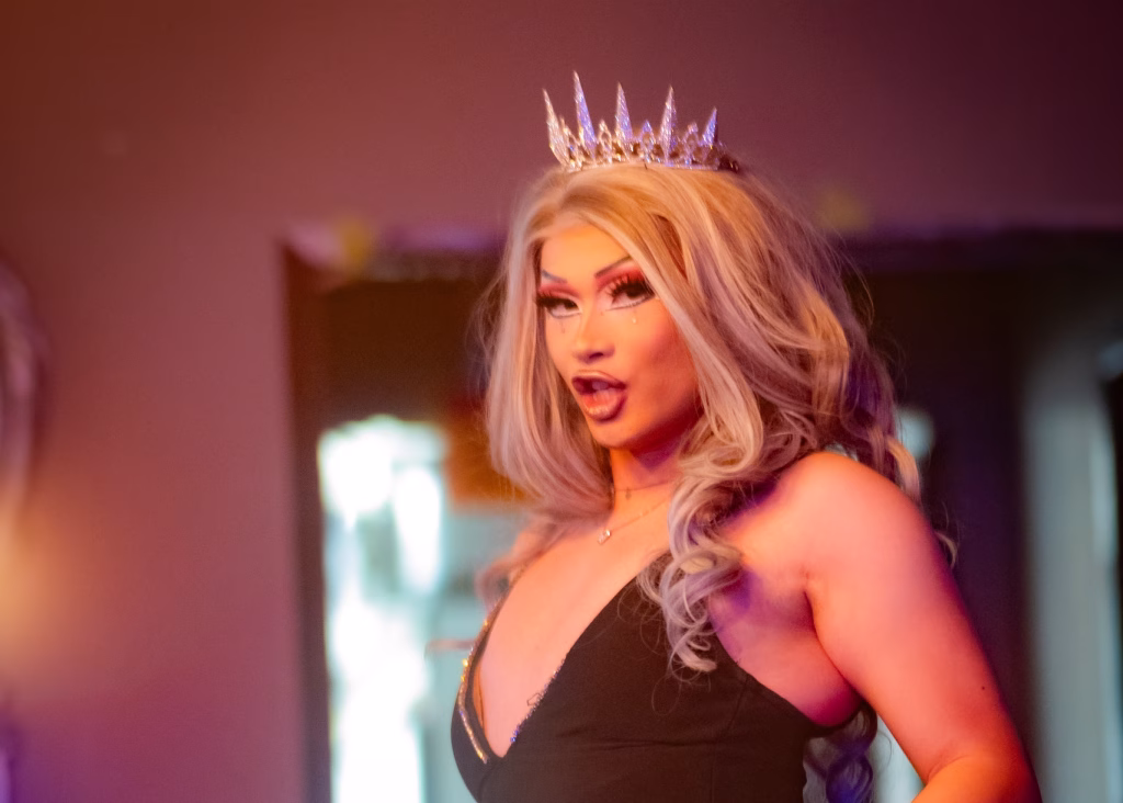Airress looking into the camera as she performs in a black dress with jeweled tiara.